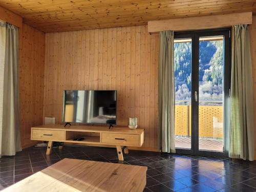 Ferienapartment Fieschertal في Fieschertal: غرفة معيشة مع تلفزيون بشاشة مسطحة على جدار خشبي