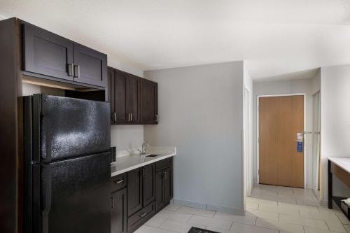 a kitchen with black cabinets and a black refrigerator at Best Western PLUS Mountain View Auburn Inn in Auburn