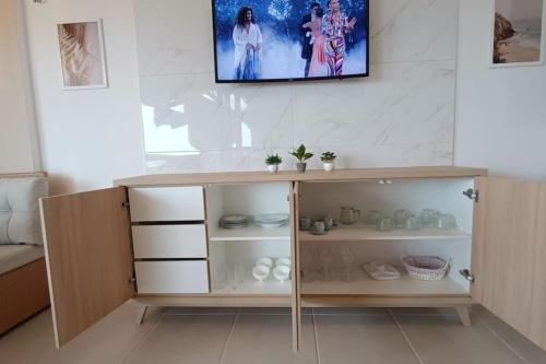 a wooden cabinet with a tv on the wall at Flat Malua - Apartamento Pé Na Areia Com Vista Mar Taíba-CE in Taíba