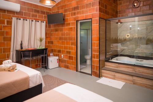 uma casa de banho com uma banheira numa parede de tijolos em Pousada Pitauá em Socorro