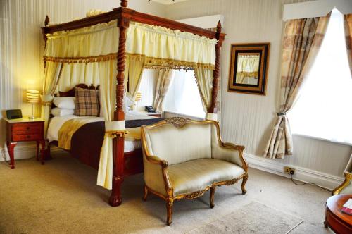 a bedroom with a canopy bed and a chair at The Hotel Commodore in Llandrindod Wells