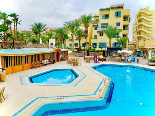 a pool at a resort with palm trees and buildings at Eagles Downtown Resort in Hurghada