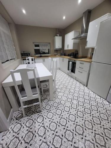a kitchen with a white table and white chairs at 4 Bedrooms, 8 min to Manchester City! in Manchester