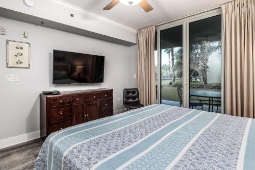um quarto com uma cama e uma televisão de ecrã plano em Waterscape C206 Ground Floor em Fort Walton Beach