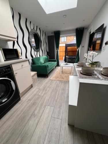 a kitchen and living room with a green couch at Home from home The Orchid with Hot tub in Colnbrook