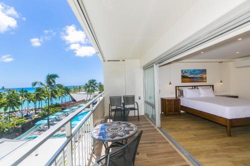 een slaapkamer met een bed en een balkon met uitzicht op de oceaan bij Ilikai Tower 438 Lagoon View 1BR in Honolulu