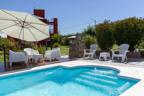 una piscina con sillas y sombrilla en Punta Piedra cabañas & suites en Los Reartes