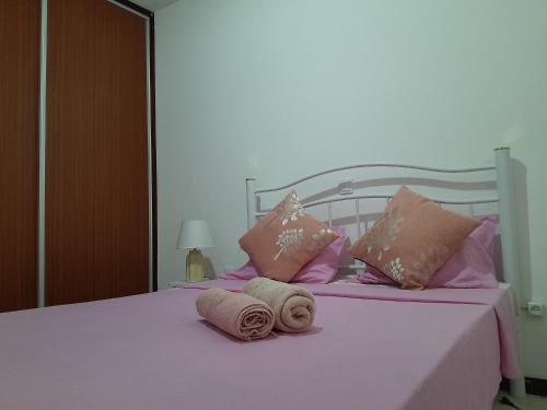 Una cama blanca con almohadas rosas y toallas. en AP Hélder Bentub, en Ponta do Sol