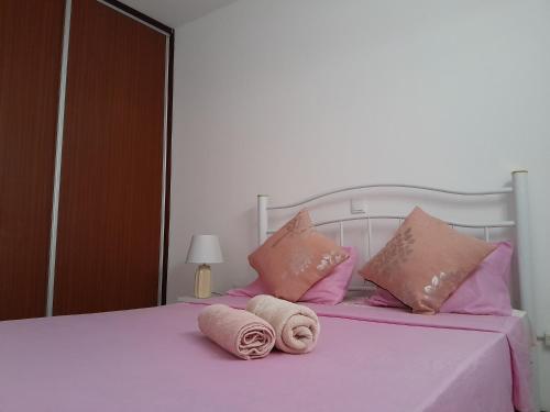 uma cama com almofadas cor-de-rosa e toalhas em AP Hélder Bentub em Ponta do Sol