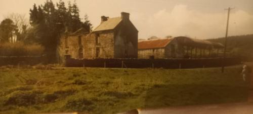 an old stone building in a field with a house at Bealkelly Country House in Killaloe