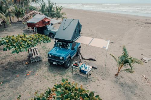 un camion bleu garé sur une plage avec une tente dans l'établissement 4BOX4 - 4x4 Car Rentals Only - SJO Airport, à Santiago Este