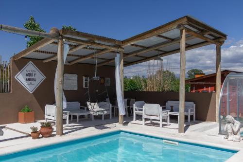 a pavilion with a pool and chairs and a table at Punta Piedra cabañas & suites in Los Reartes