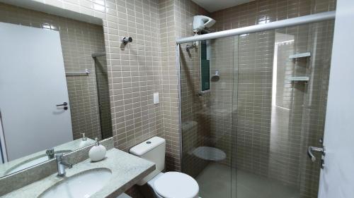 La salle de bains est pourvue de toilettes, d'un lavabo et d'une douche. dans l'établissement Areias do Mar | 2 Quartos, Terraço e Frente ao Mar A102, à Barra de São Miguel