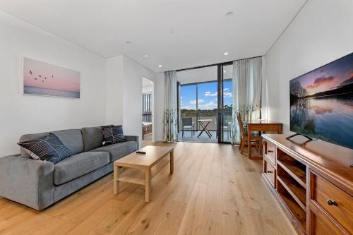 a living room with a couch and a flat screen tv at Central location one bedroom in Chatswood in Sydney