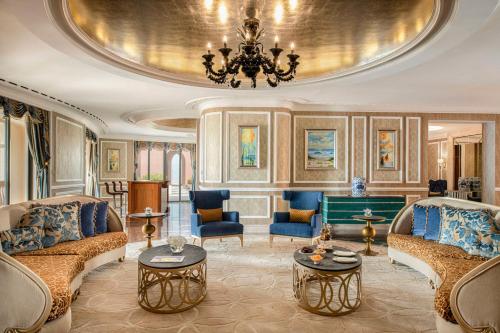 a living room with two couches and a chandelier at Marsa Malaz Kempinski, The Pearl in Doha