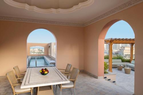 a dining room with a table and chairs and a pool at Marsa Malaz Kempinski, The Pearl in Doha