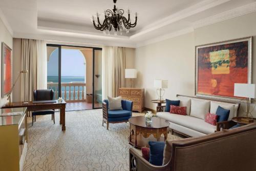 a living room with a couch and a chandelier at Marsa Malaz Kempinski, The Pearl in Doha