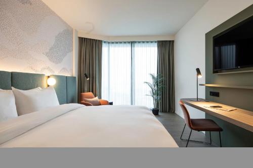 a hotel room with a large bed and a desk at voco Brussels City North by IHG in Vilvoorde