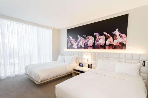 a hotel room with two beds and a large window at HALL Arts Hotel Dallas, Curio Collection by Hilton in Dallas