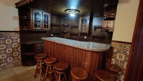 eine Küche mit einer Bar mit Holzhockern in der Unterkunft Orion Guest Villa Casais in Lousada