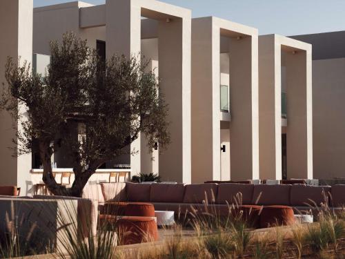 a building with a couch and a tree in front at The Royal Senses Resort & Spa Crete, Curio Collection by Hilton in Panormos Rethymno