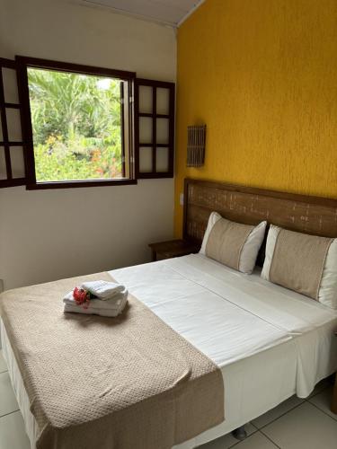 a bedroom with a large bed with a window at Pousada Alforria in Búzios