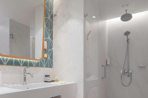 a bathroom with a shower and a sink and a mirror at The Emerald House Lisbon - Curio Collection By Hilton in Lisbon