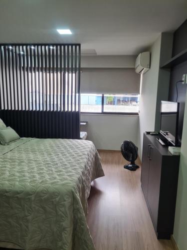 a bedroom with a bed and a desk and a television at Flat Praia da Costa in Vila Velha