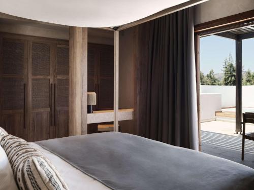 a bedroom with a large bed and a balcony at Lindian Village All Inclusive Resort Rhodes,Curio Collection in Kiotari
