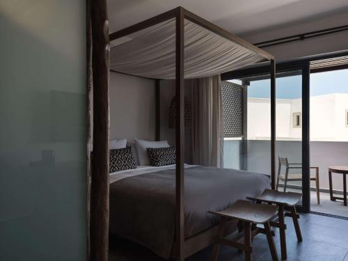 a bedroom with a canopy bed and a balcony at Lindian Village All Inclusive Resort Rhodes,Curio Collection in Kiotari
