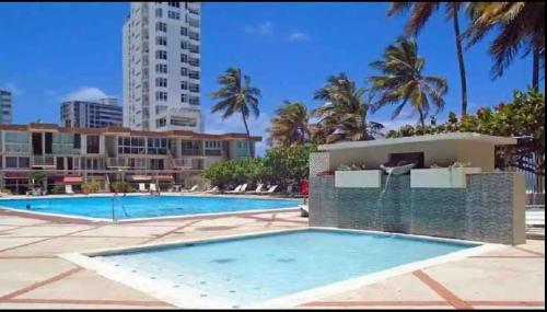 a swimming pool at a resort with palm trees at Condado Beach-Pool Front Jewel in San Juan