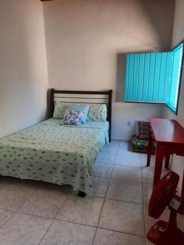 um quarto com uma cama e uma mesa vermelha em Casa da Bru pertinho da praia e da lagoa em Rio das Ostras