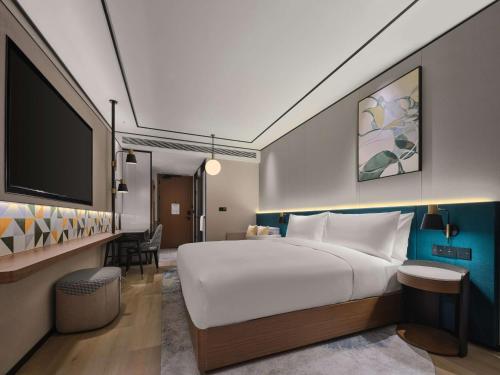 um quarto de hotel com uma cama grande e uma televisão de ecrã plano em Hilton Garden Inn Hangzhou West Lake em Hangzhou