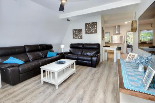 a living room with a black leather couch and a table at Adalene-56 Phillip Drive South West Rocks in South West Rocks