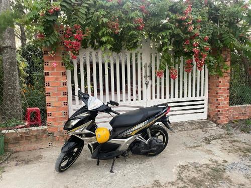 a motorcycle parked in front of a white fence at Vong Nguyet Homestay - Entire Bungalow 36m2 in Tây Ninh