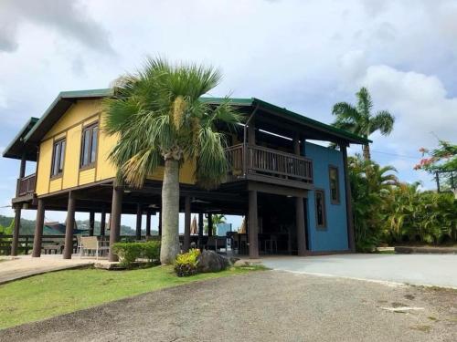 a yellow and blue house with a palm tree at Villa Tesoro at Carabali in Luquillo