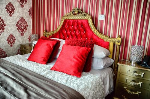 a bed with a red headboard and red pillows at The Hotel Commodore in Llandrindod Wells