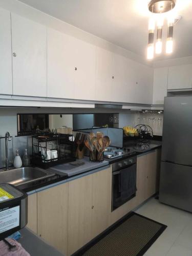 a kitchen with white cabinets and a stove top oven at Saint Honore Executive: 6 guests, 5 beds, 2 bedrooms, 2 bathrms in Iloilo City