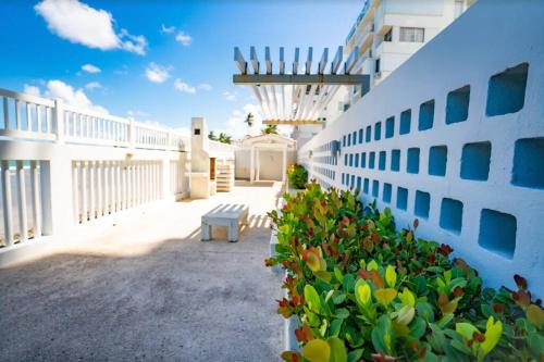 a white building with a bench in a courtyard at Enchanted Honeymoon Isla Verde Beachfront in San Juan