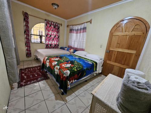 um quarto com uma cama e uma porta de madeira em Hostal flor del lago em Panajachel