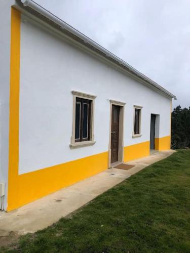 a white and yellow building with a door and grass at Quinta da Casa Azul in Óbidos