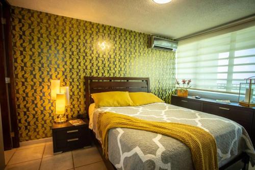 a bedroom with a bed with a yellow blanket on it at Enchanted Jewel 9 Beachfront Pool in Luquillo
