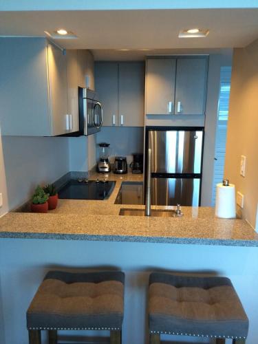 a kitchen with a counter with two stools and a refrigerator at Enchanted 17 Jewel Beachfront Luquillo -Pool in Luquillo