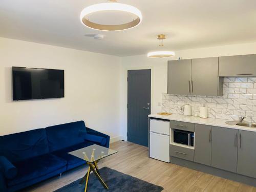 een woonkamer met een blauwe bank en een keuken bij Roomello luxury City Studios in Peterborough