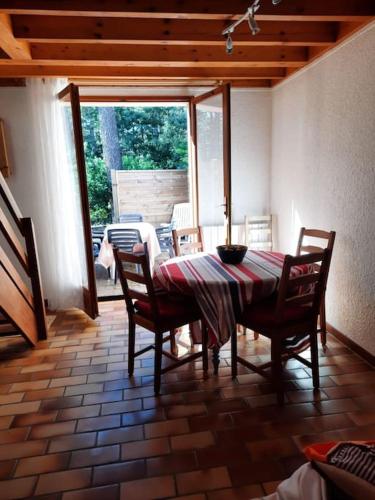 une salle à manger avec une table et des chaises ainsi qu'une terrasse dans l'établissement Maison d'été familiale, piscine dans la résidence, à Lacanau