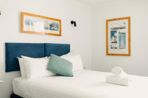 a bedroom with a white bed with a blue headboard at Shipwrights Arms Hotel in Hobart
