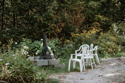 two white chairs and a fireplace in a garden at Chalet rétro Avec Spa in Chertsey