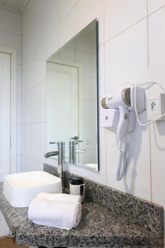 a bathroom with a sink and a blow dryer on a counter at Aldeia Flor de Liz - Pedra Azul in Pedra Azul