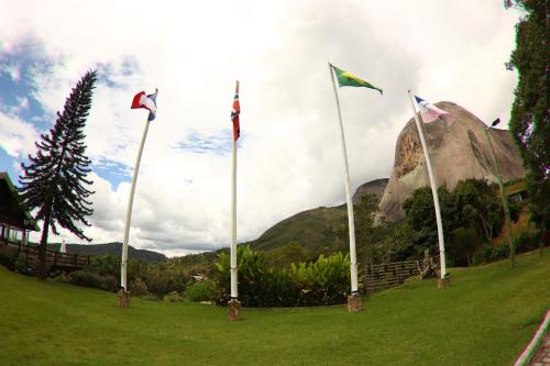 a group of flags in a field with a mountain at Aldeia Flor de Liz - Pedra Azul in Pedra Azul