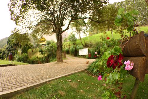 a park with flowers and a tree and a sidewalk at Aldeia Flor de Liz - Pedra Azul in Pedra Azul